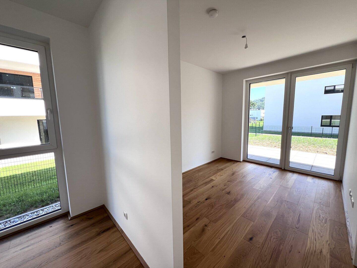 Helles Schlafzimmer mit Holzboden und mehreren Fenstern, die viel Tageslicht hereinlassen.