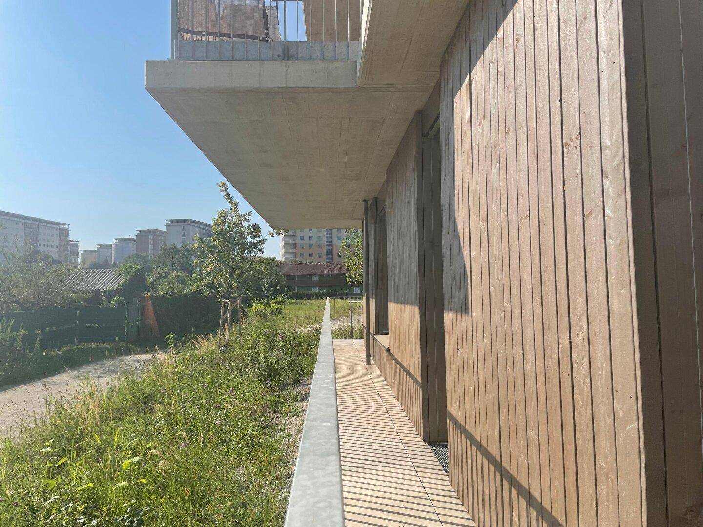 Langer Terrassenbereich mit Holzverkleidung und weitem Blick ins Grüne, ideal zum Entspannen.