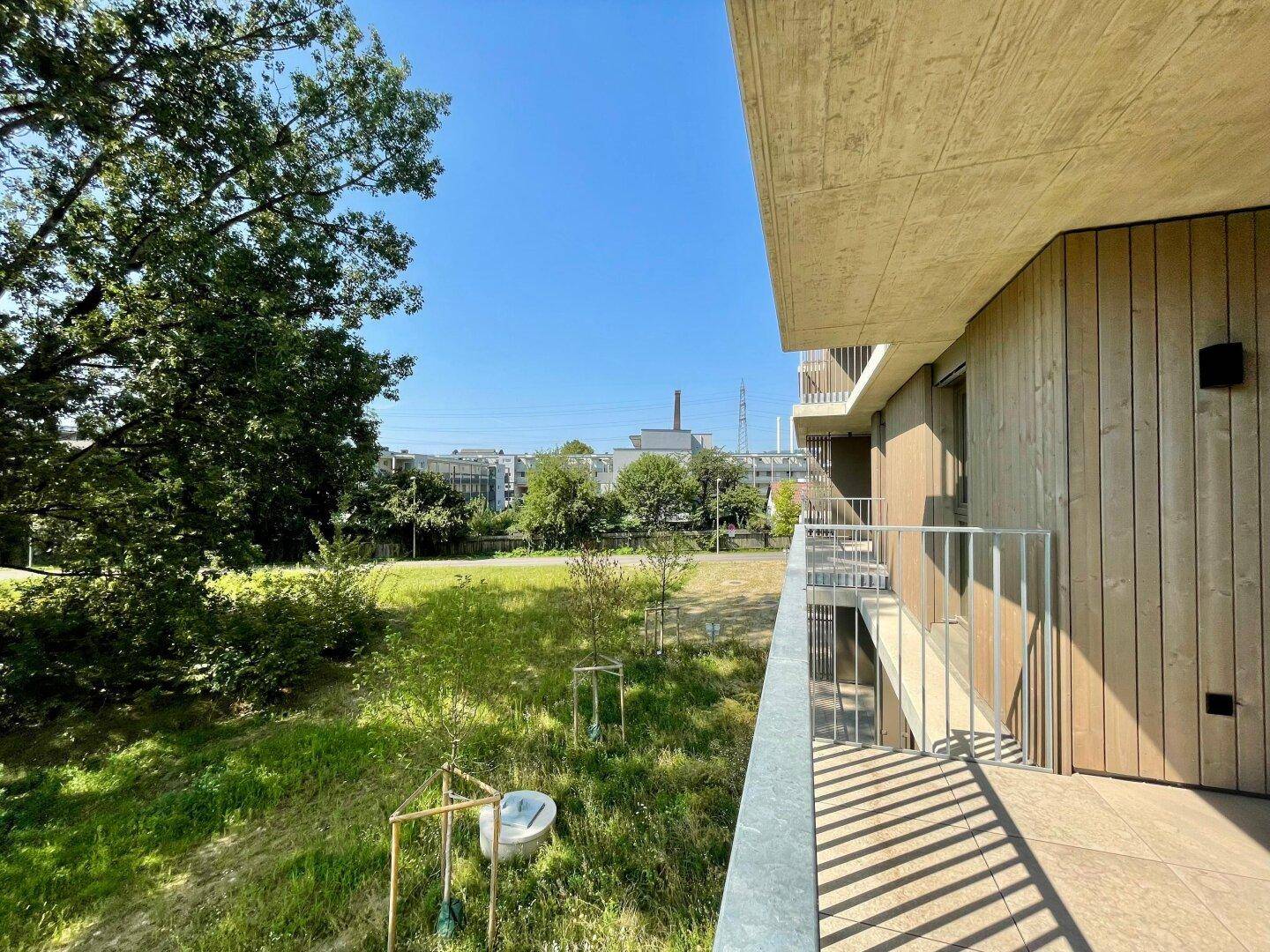 Geräumiger Balkon mit Holzelementen und weitem Blick ins Grüne.