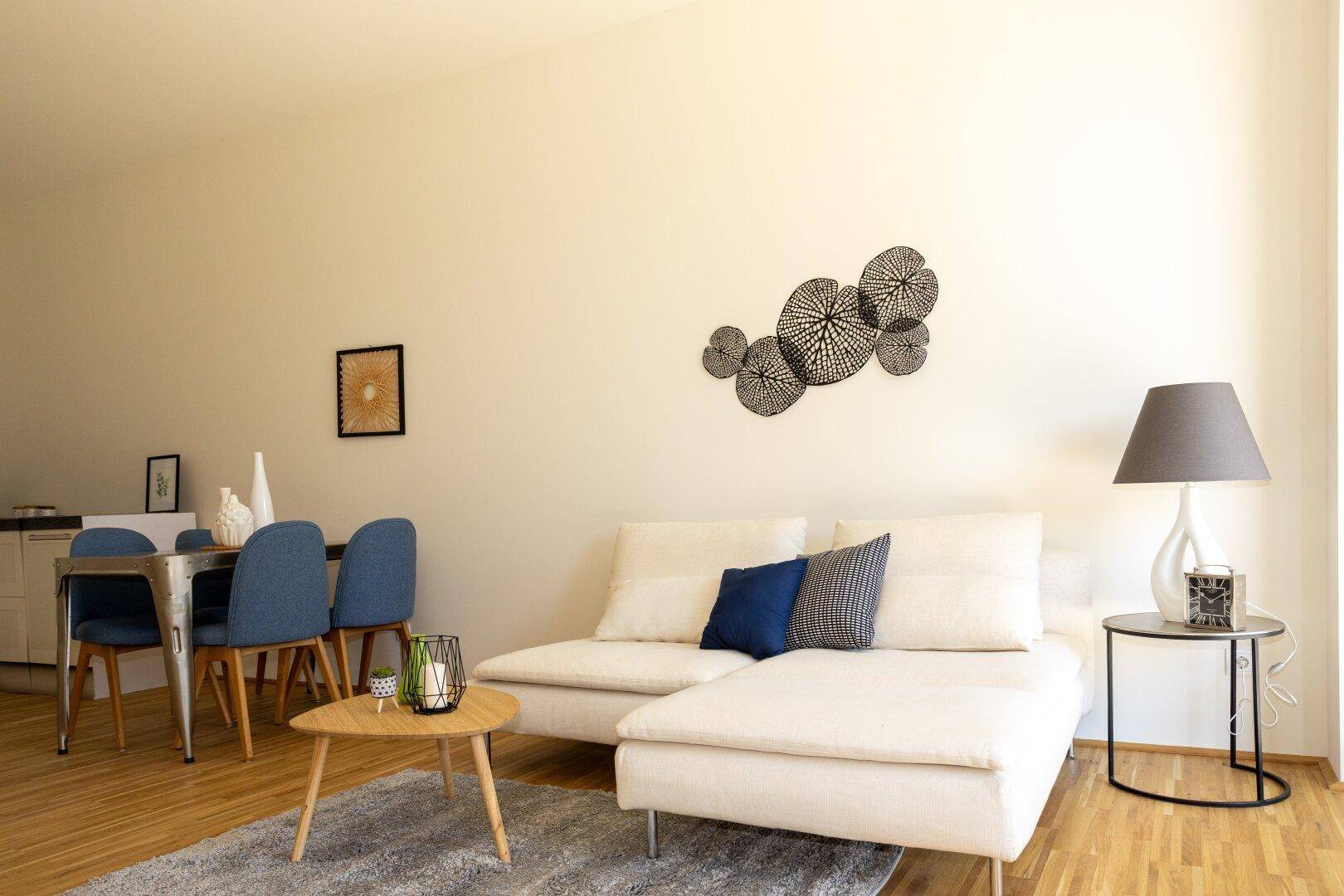 Gemütlicher Wohnbereich mit Sofa, Couchtisch und Essbereich im Hintergrund.