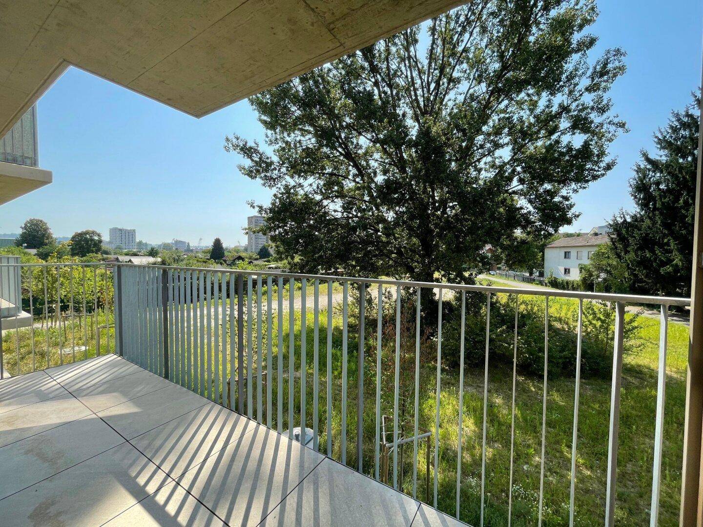 Balkon mit Fliesenboden und weitem Blick ins Grüne und auf die Umgebung.