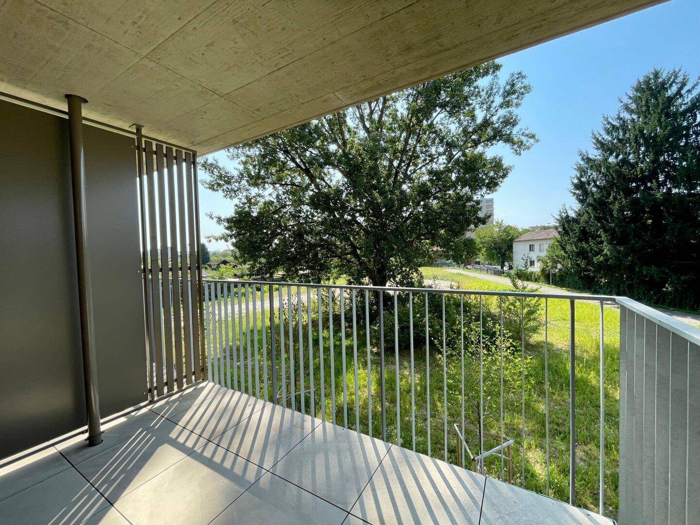 Heller Balkon mit Fliesenboden und weitem Blick ins Grüne, ideal zum Entspannen.