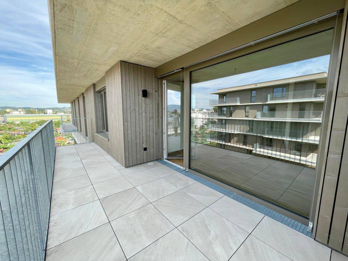 Heller Balkon mit moderner Architektur und weitem Blick über die Stadt und die grüne Umgebung.