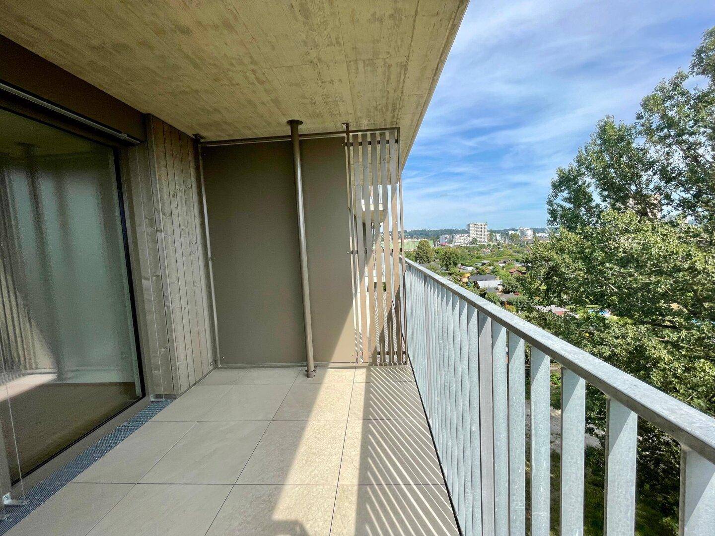 Geräumiger Balkon mit Fliesenboden und weitem Blick über die Stadt und Kleingärten.
