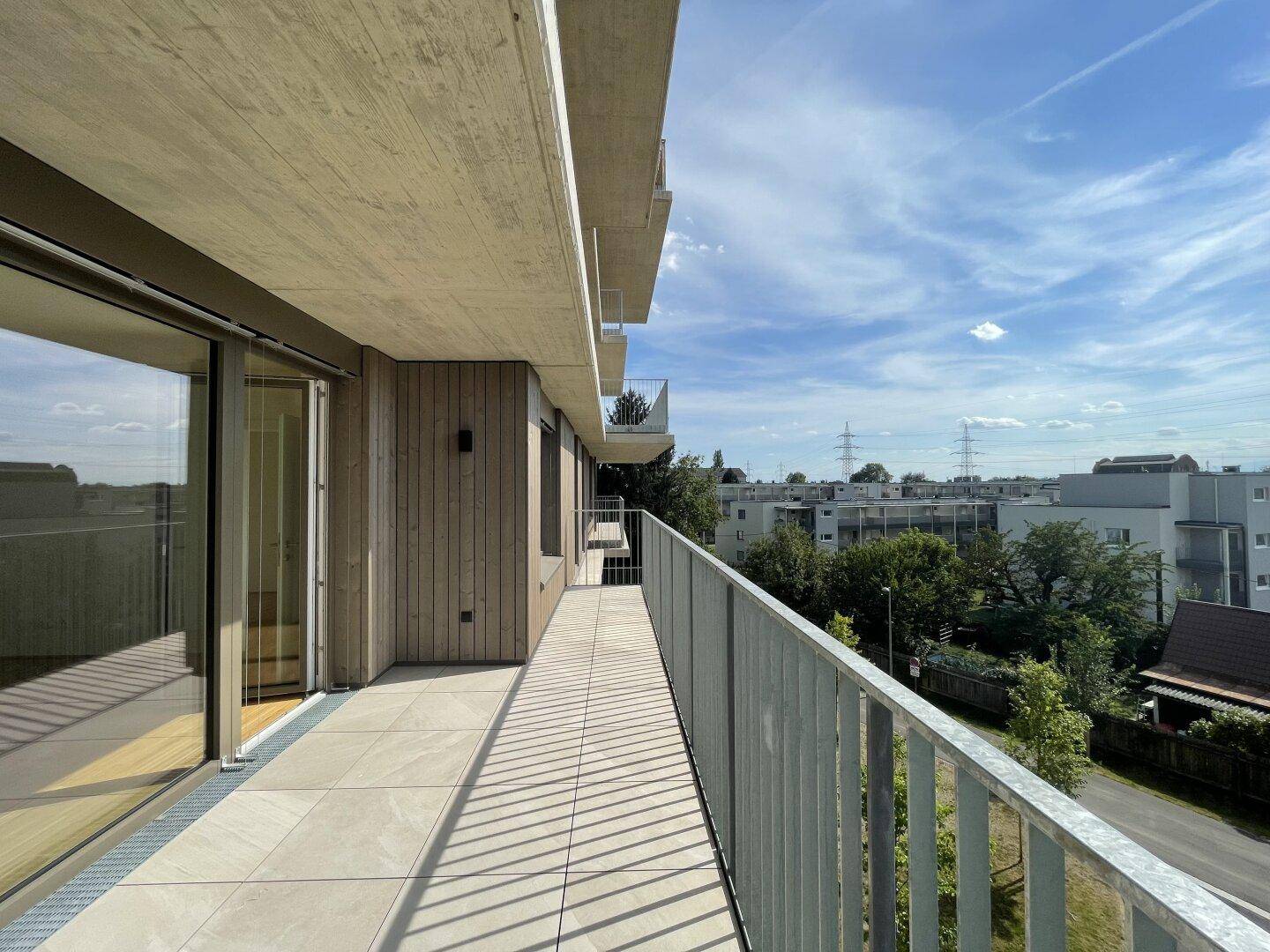 Langer Balkon mit Fliesenboden und Metallgeländer, bietet einen weiten Blick auf die Umgebung.