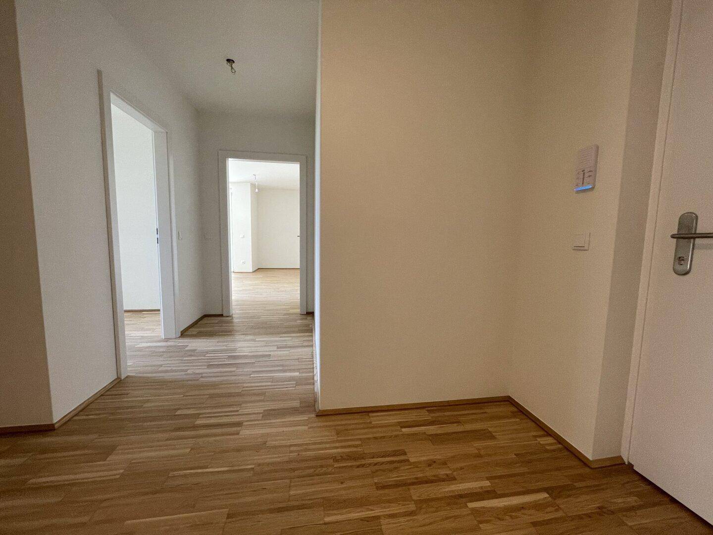 Heller Flur mit hellem Parkettboden, der zu weiteren Zimmern der Wohnung führt.
