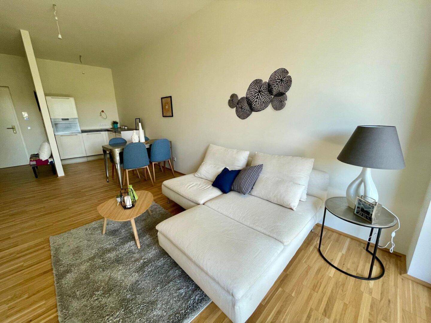 Gemütlicher Wohnbereich mit Sofa und Blick auf den Essbereich sowie eine offene Küche.