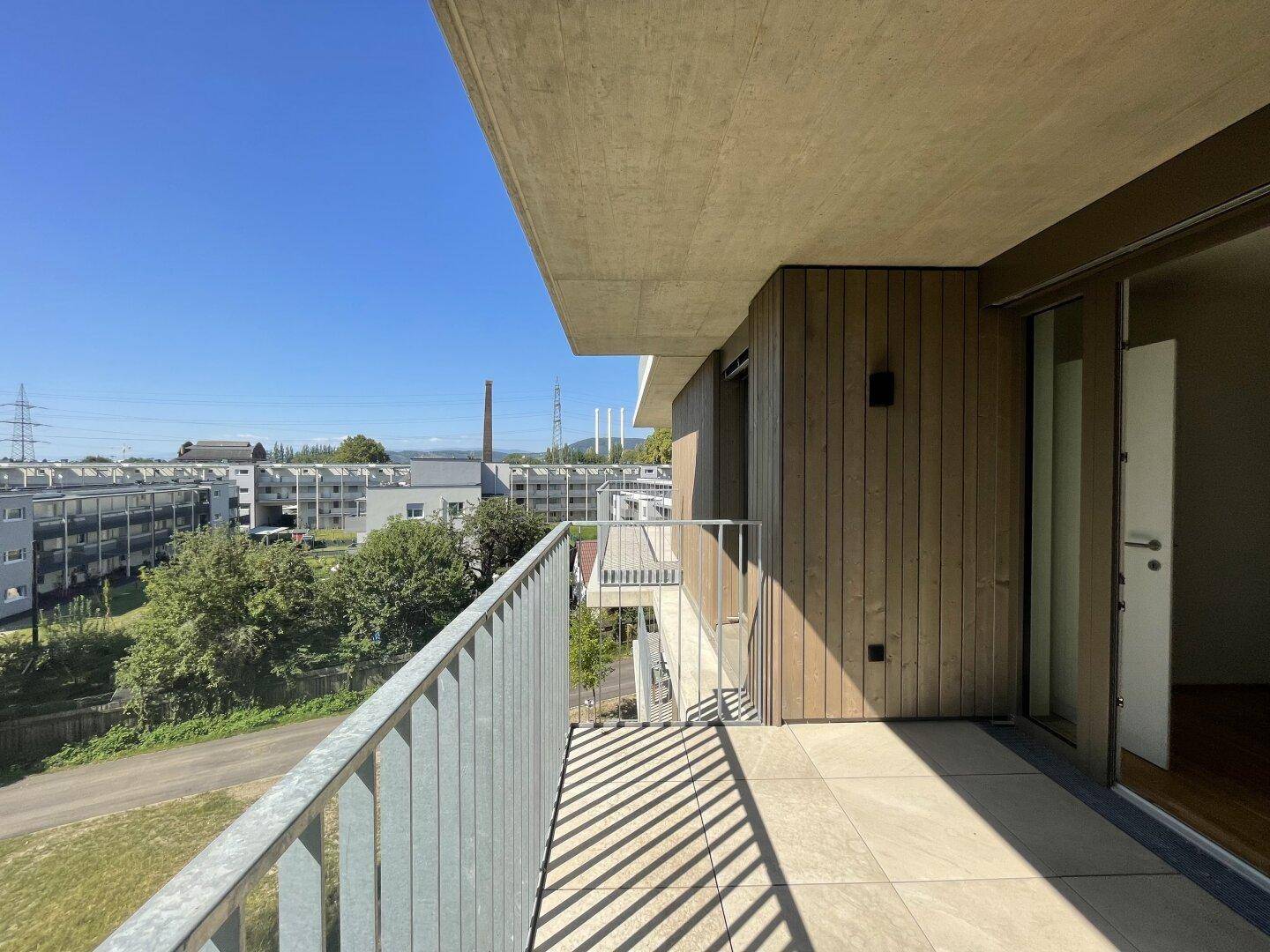 Sonniger Balkon mit Fliesenboden und weitem Blick über die Umgebung.
