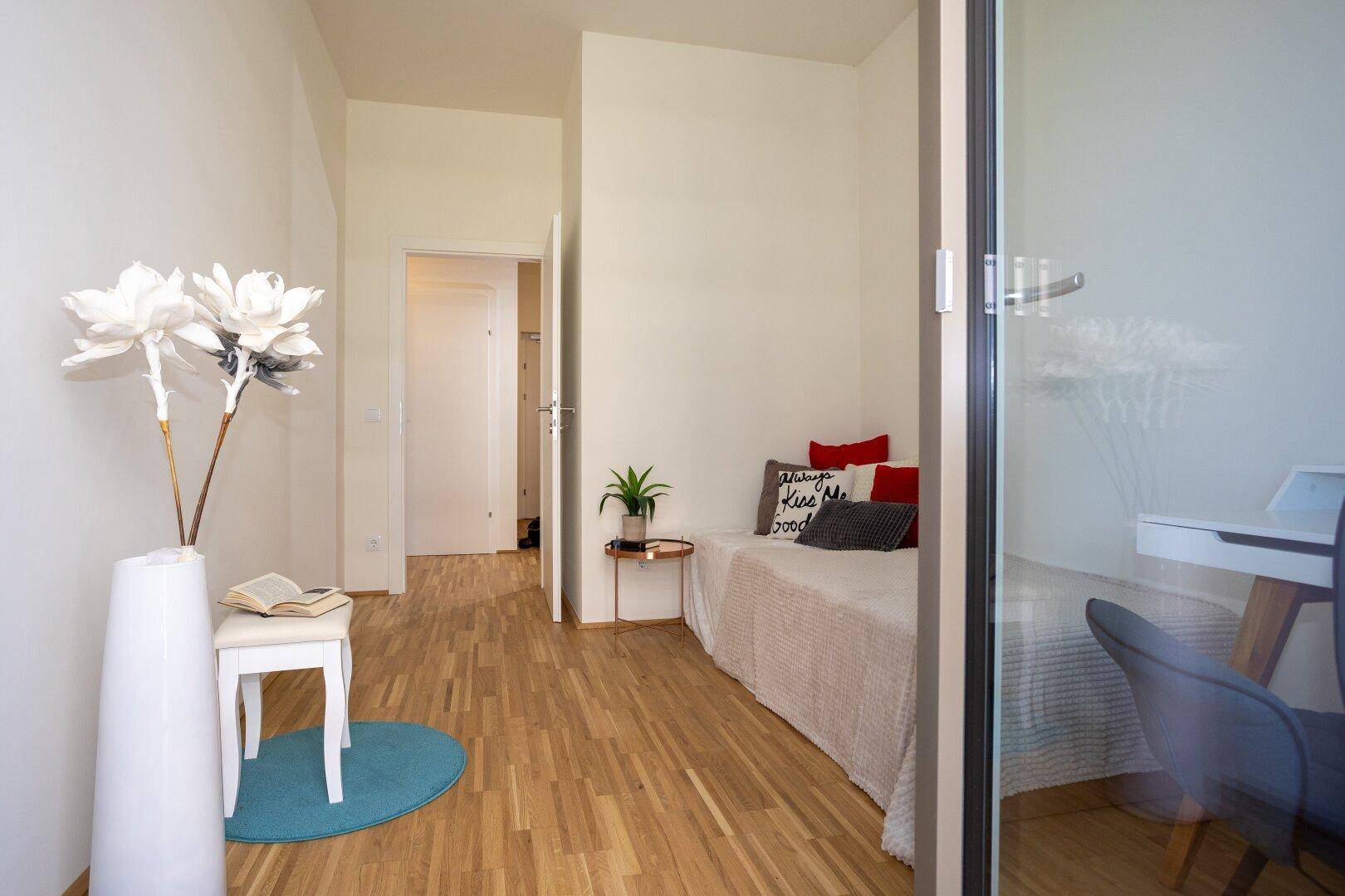Gemütliches Schlafzimmer mit Holzboden und schlichtem Design, ideal als Gästezimmer.
