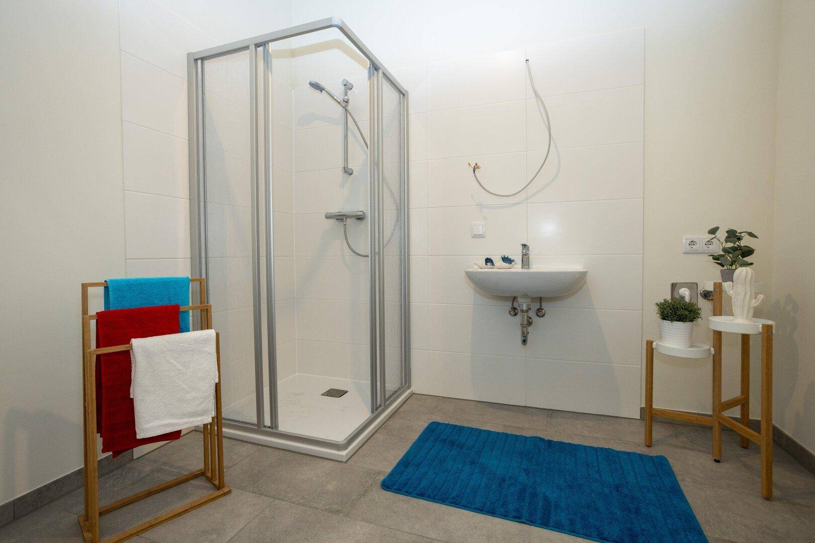 Modernes Badezimmer mit Duschkabine, Waschbecken und hellen Fliesen.