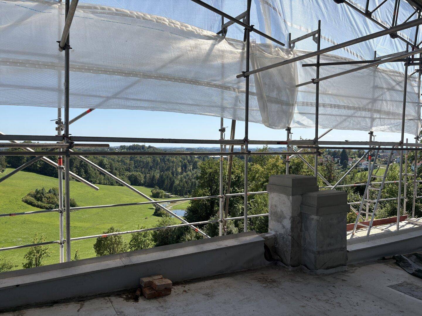 Aussicht von der Baustelle auf eine weite grüne Landschaft mit einem See in der Ferne.