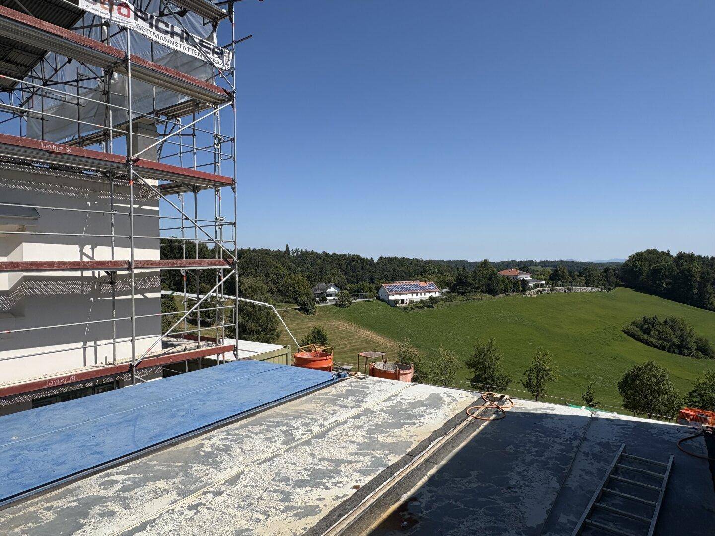 Panoramablick von der Baustelle über die weite grüne Hügellandschaft unter klarem Himmel.