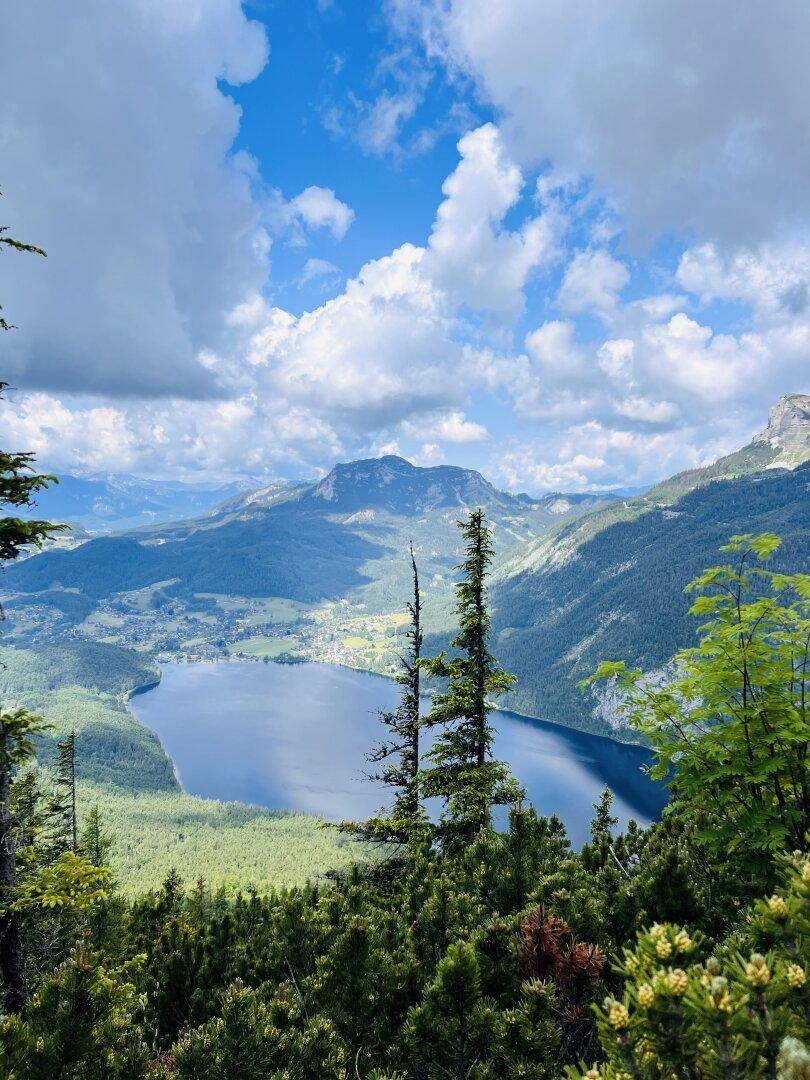 Atemberaubender Ausblick auf einen tiefblauen Bergsee, umrahmt von bewaldeten Hängen und hohen Gipfeln.