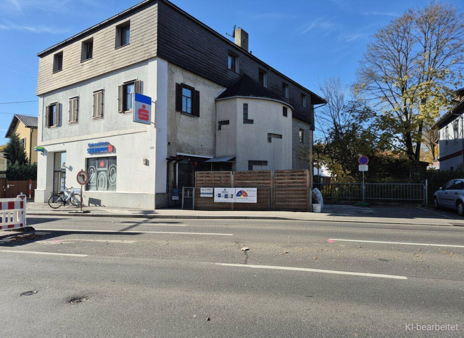 Mehrstöckiges Gebäude an einer Straße mit Geschäften im Erdgeschoss und Wohnungen darüber.