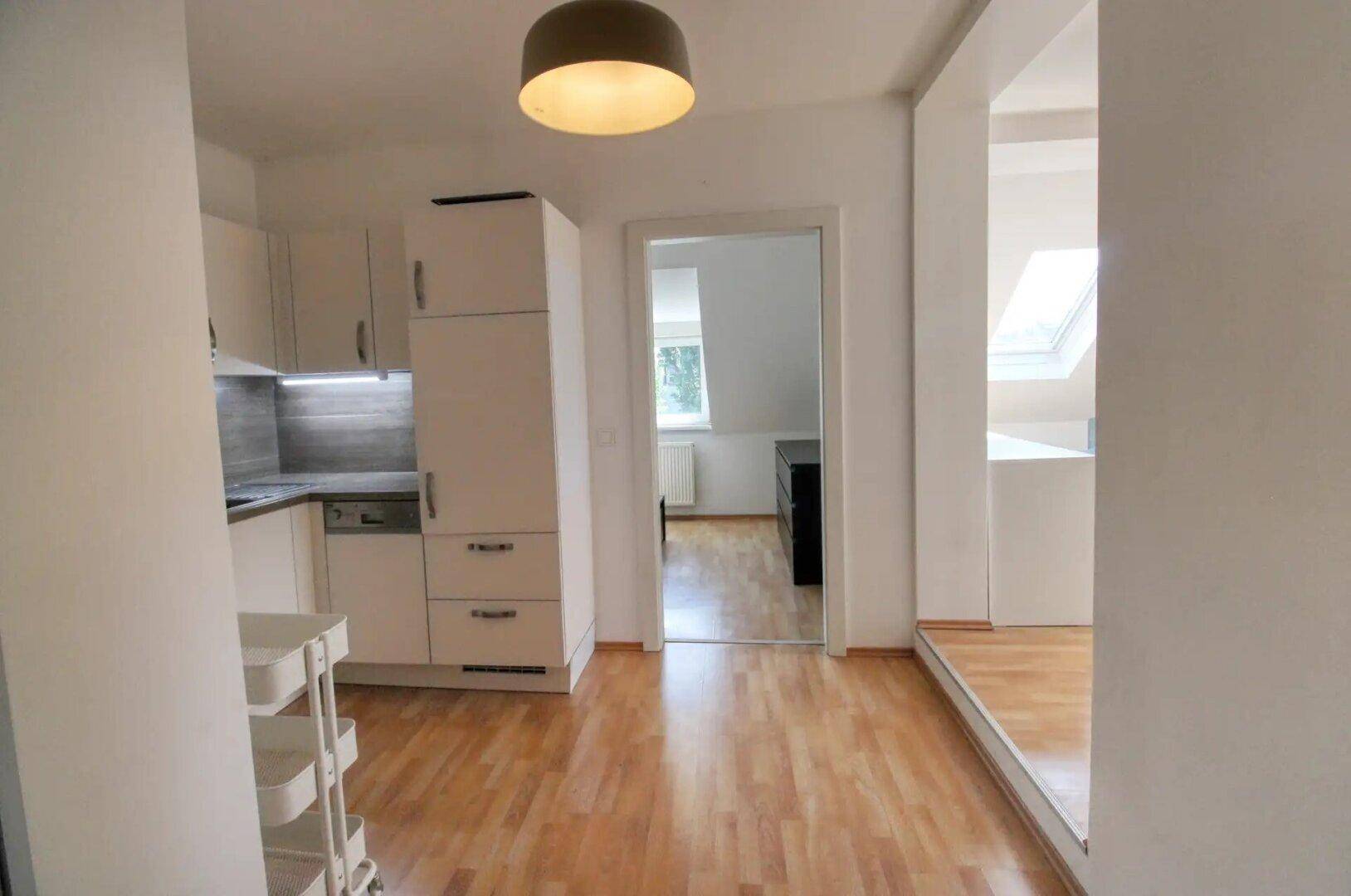 Heller Flur mit Holzfußboden, der zur Küche und einem weiteren Zimmer im Dachgeschoss führt.