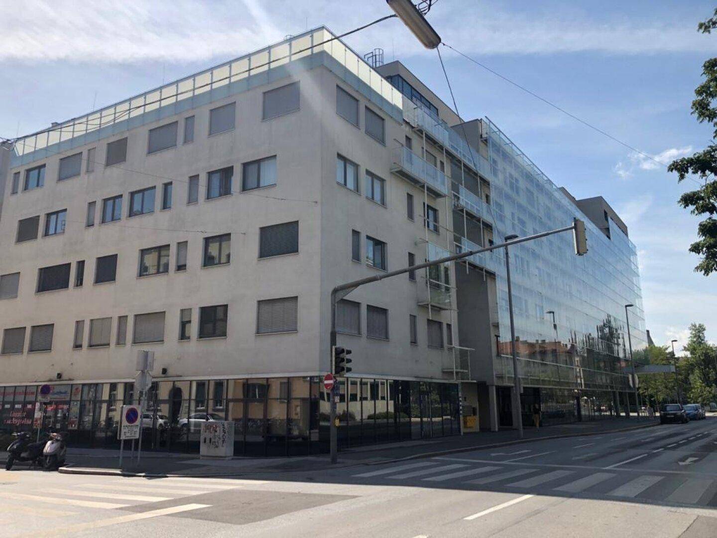 Moderne Wohngebäude-Fassade mit großen Glasflächen und Balkonen an einer städtischen Straße.