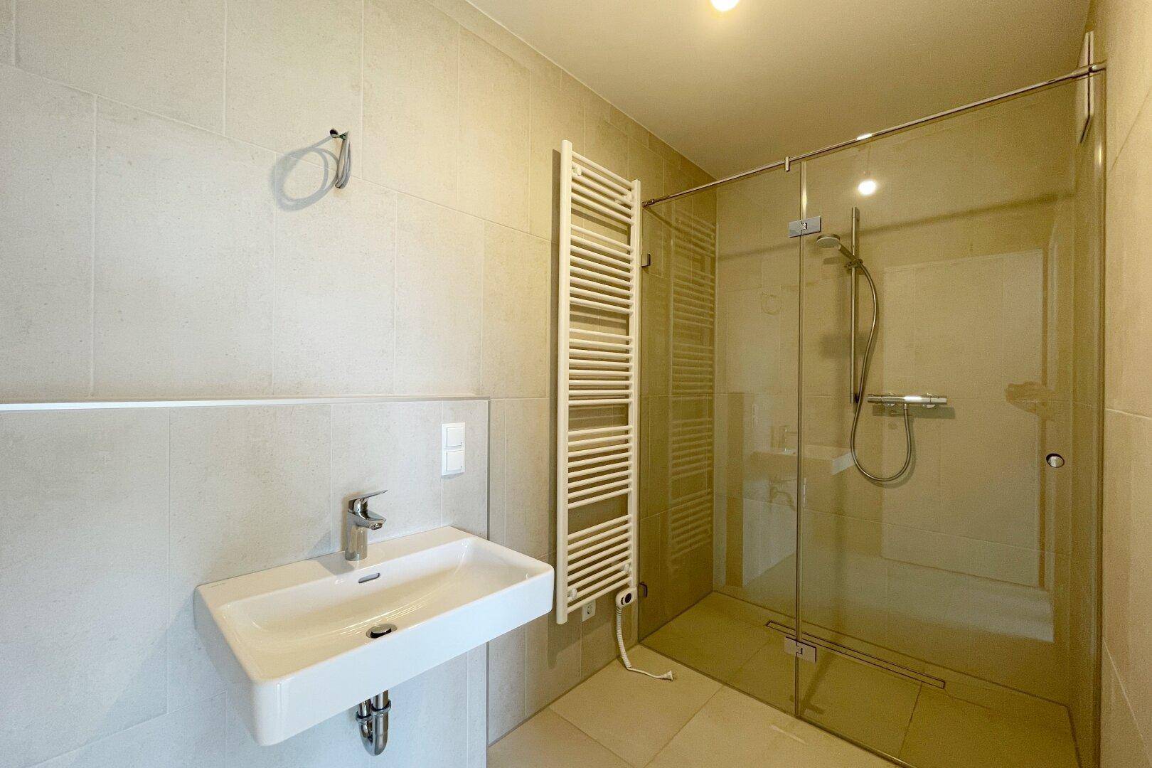 Modernes Badezimmer mit begehbarer Dusche, Einzelwaschbecken und beheiztem Handtuchhalter.