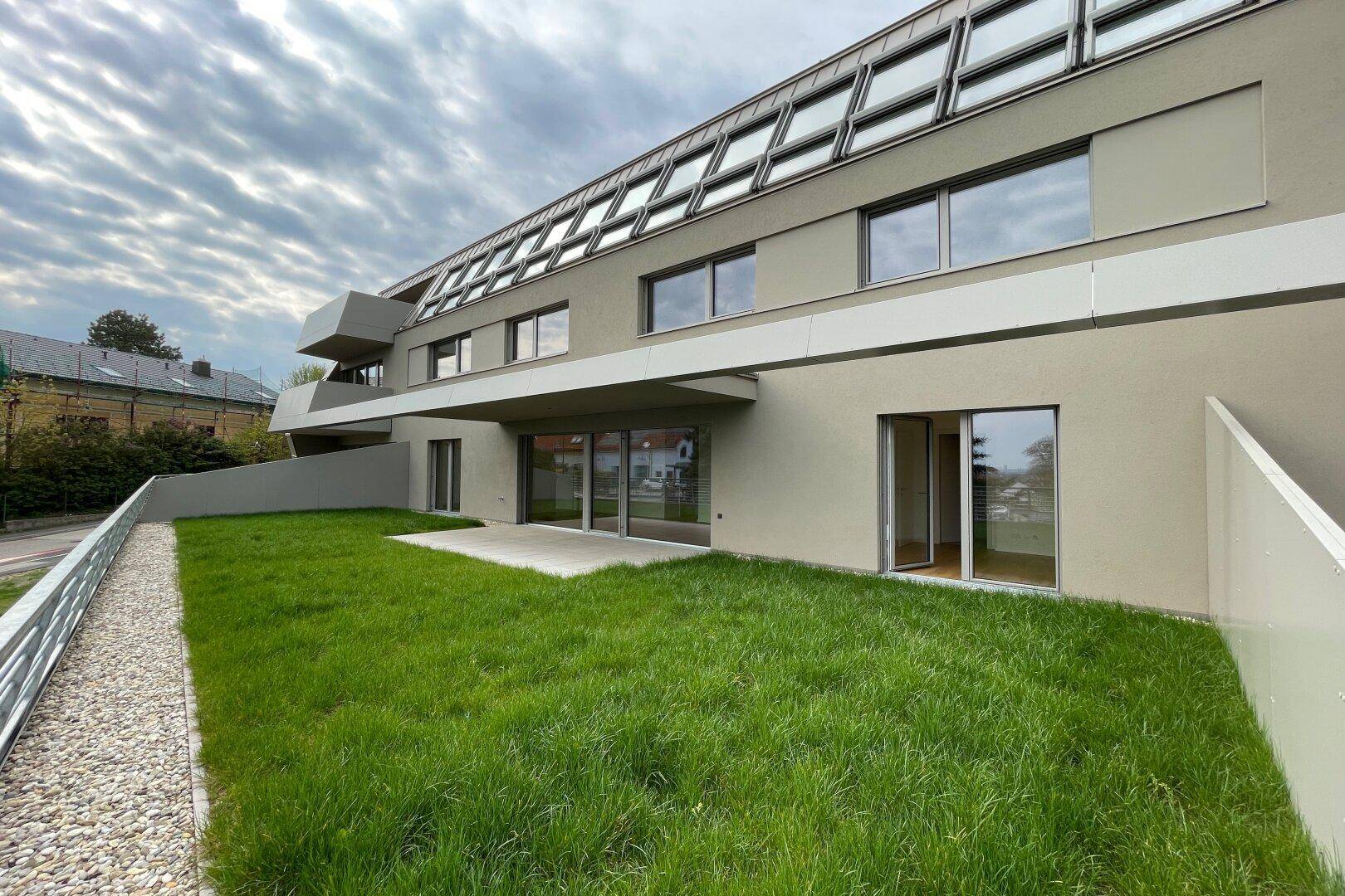 Ansicht der modernen Wohnanlage mit großen Fensterfronten und privatem Gartenbereich.