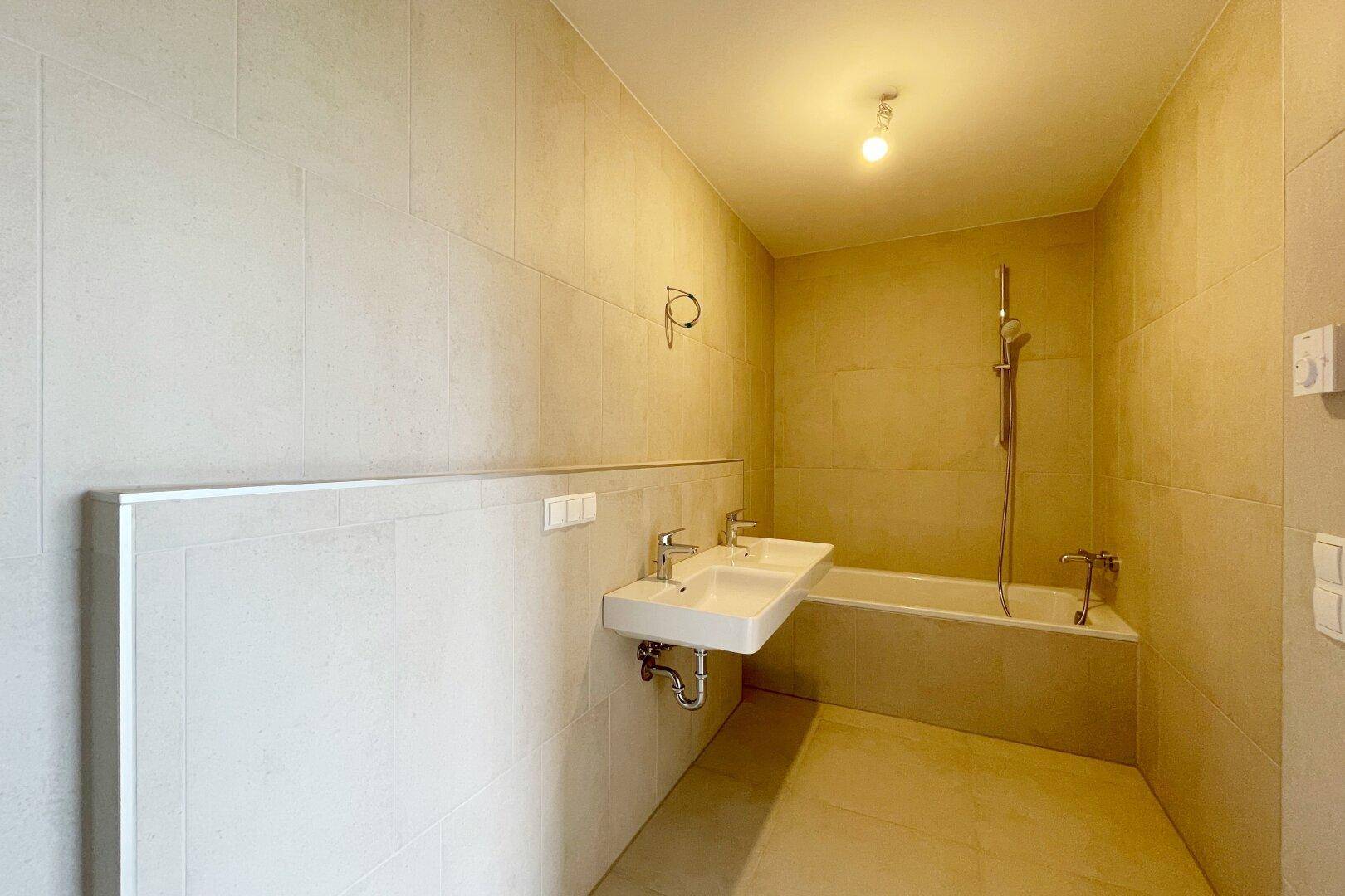Geräumiges Badezimmer mit Badewanne, Doppelwaschbecken und modernen Fliesen.