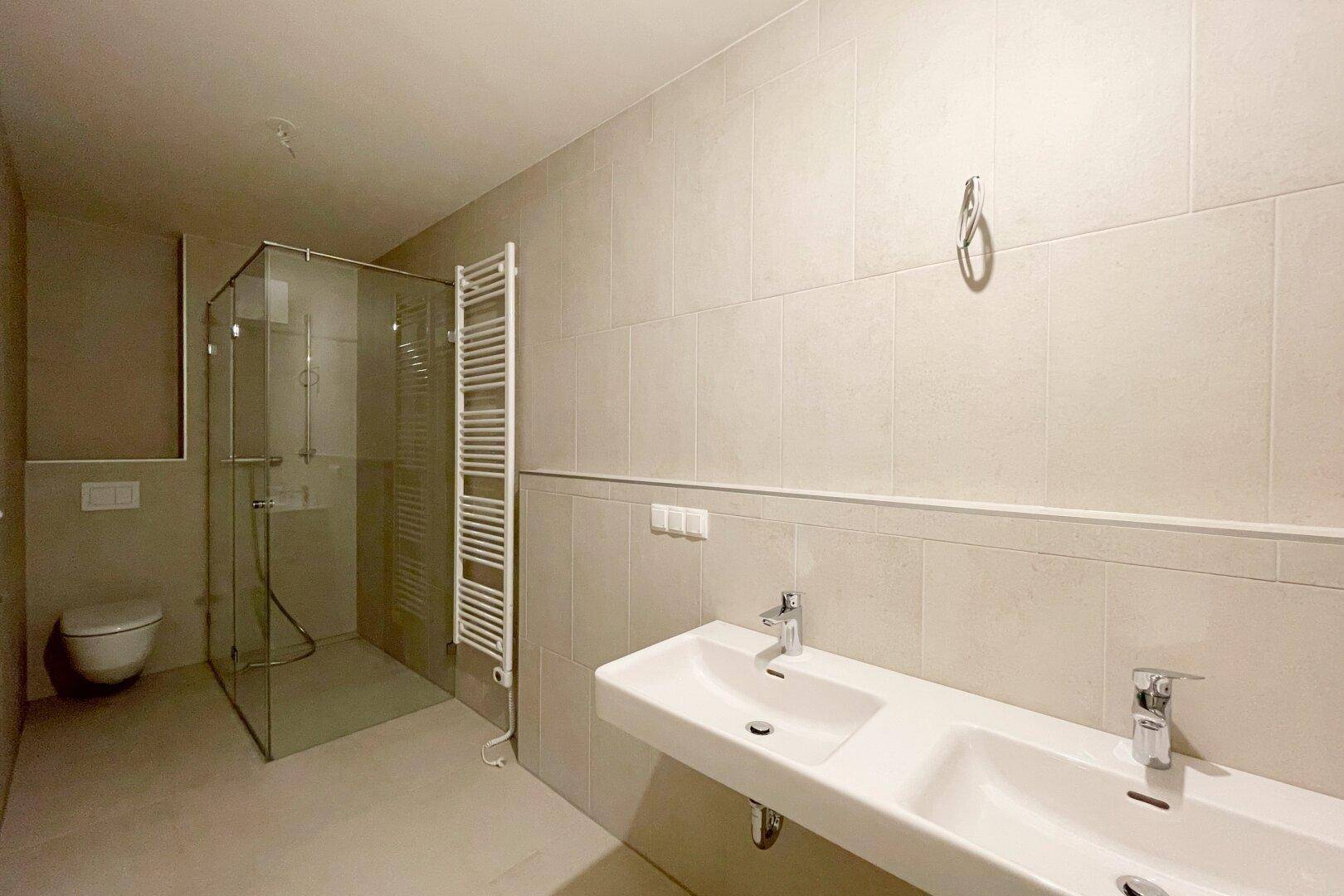 Elegantes Badezimmer mit Doppelwaschbecken, begehbarer Dusche und Wand-WC in neutralen Tönen.
