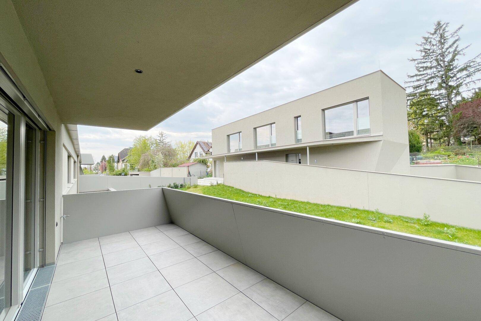 Geräumiger Balkon mit Fliesenboden und Blick auf die moderne Architektur des Gebäudekomplexes.