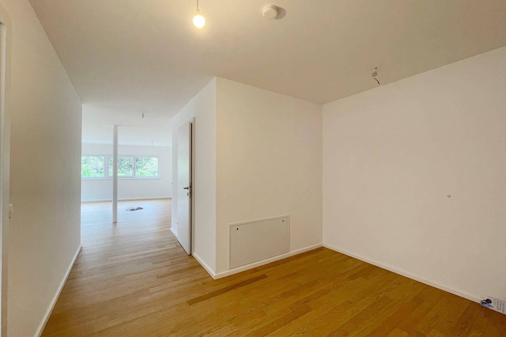 Heller Flur mit Parkettboden, der zu den verschiedenen Räumen der Wohnung führt.