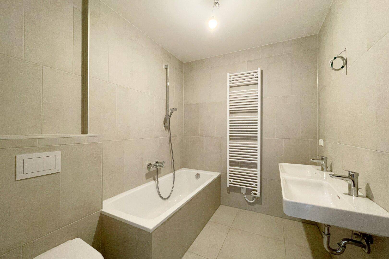 Modernes Badezimmer mit Badewanne, Doppelwaschbecken und beheiztem Handtuchtrockner.