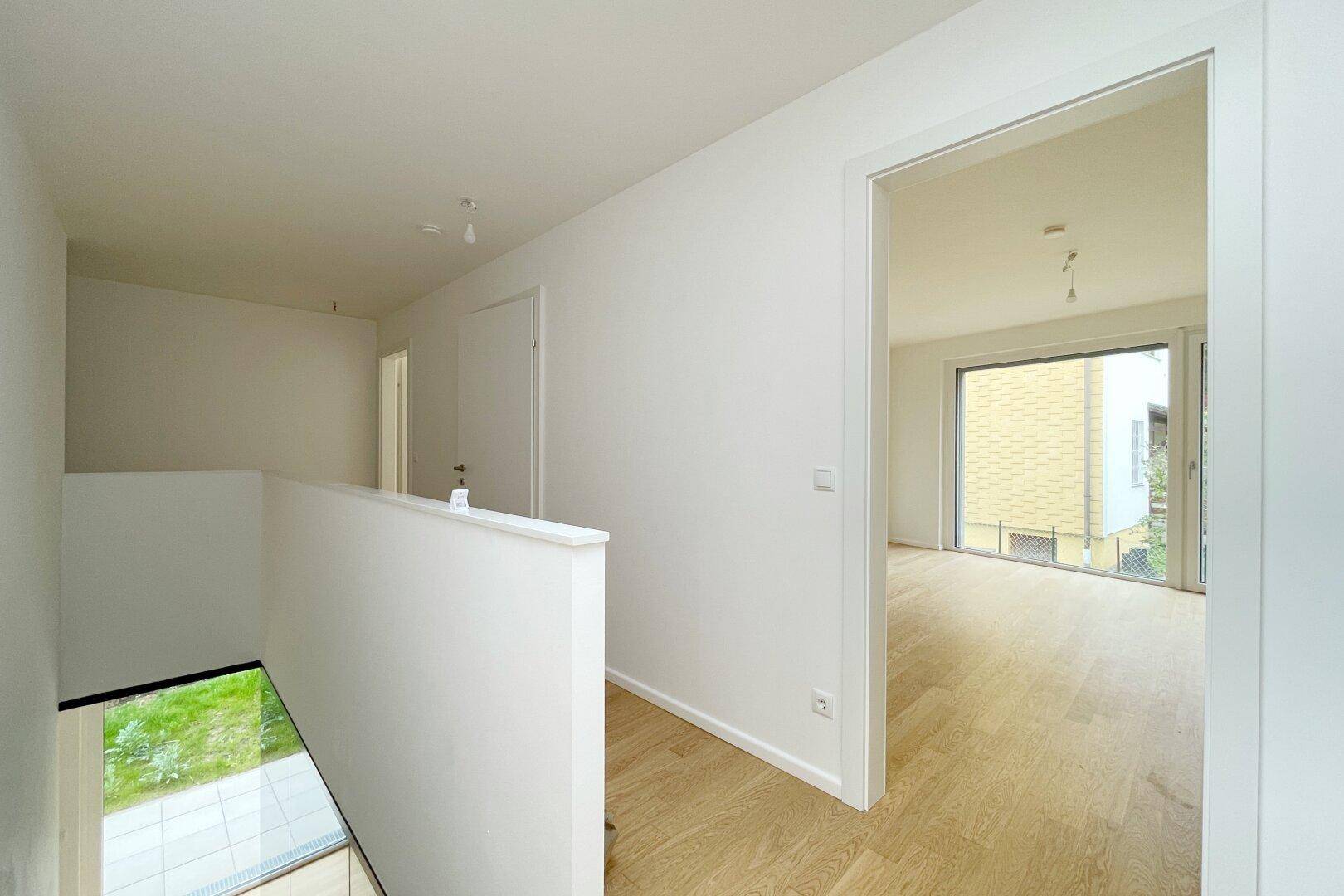 Heller Flur im Obergeschoss mit Holzparkett und Blick in ein weiteres Zimmer.