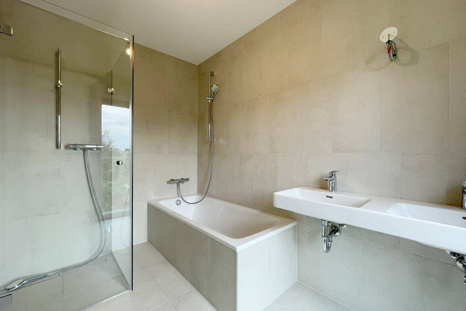 Helles Badezimmer mit Badewanne, Dusche und modernem Waschbecken.