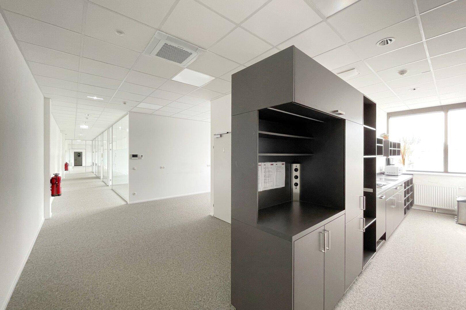 Moderne Teeküche in einem Bürobereich mit grauen Schränken und Arbeitsplatte.