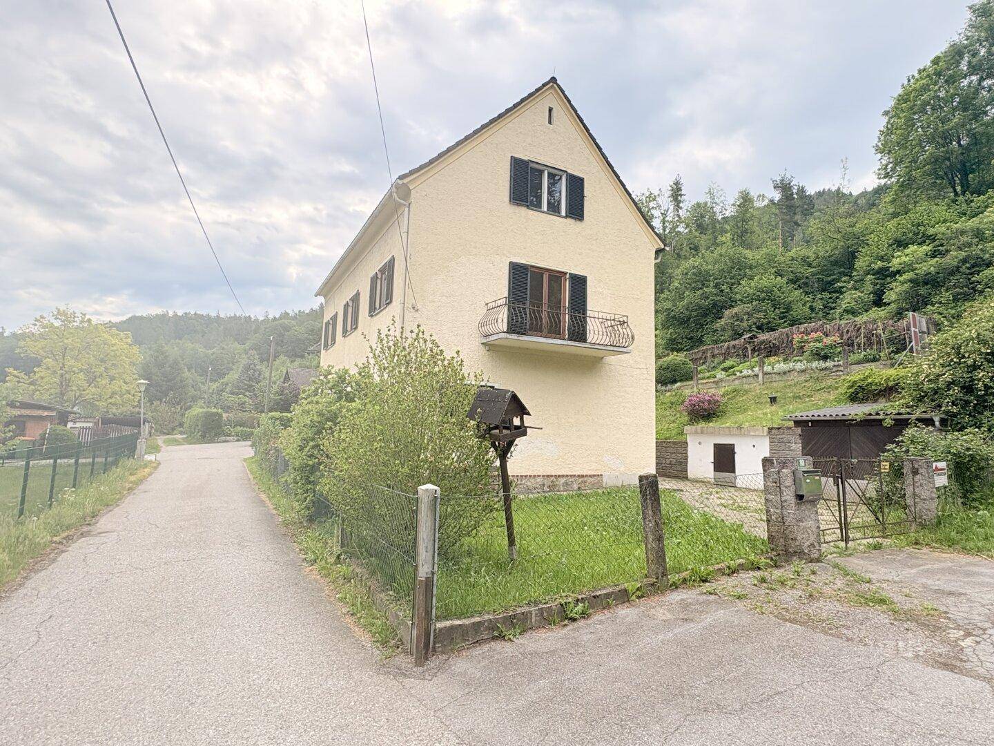 Seitenansicht des Hauses mit Garten, Balkon und Blick auf die Hügellandschaft.