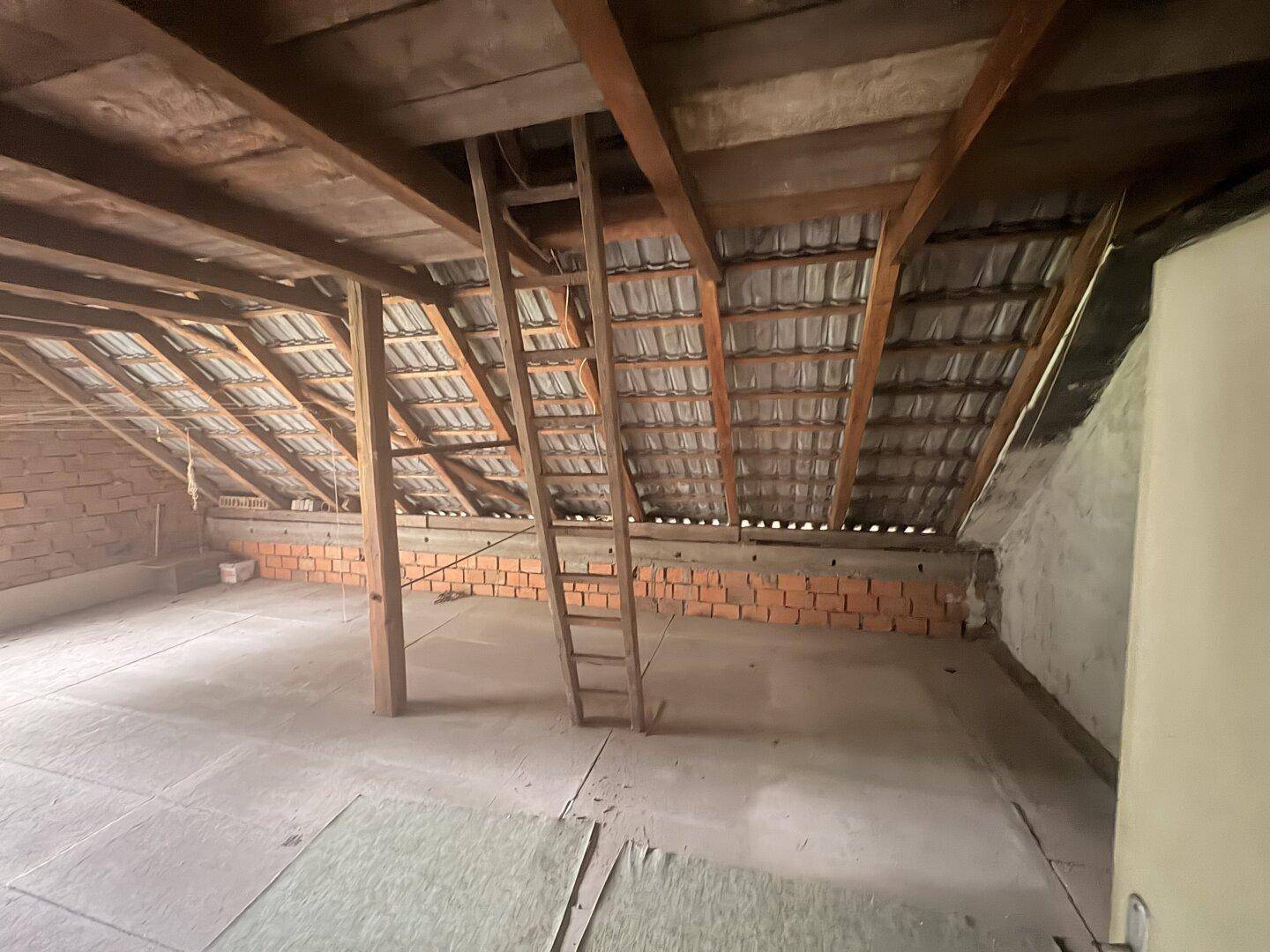 Unausgebauter Dachboden mit sichtbarer Dachkonstruktion und Ziegeln.
