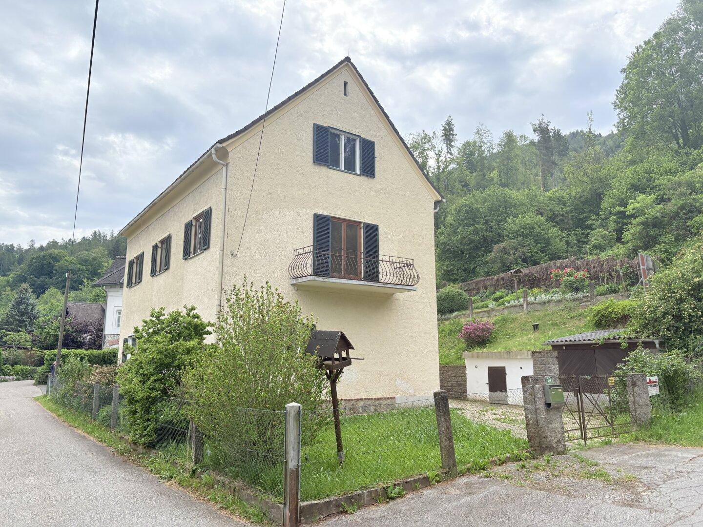 Seitenansicht des Hauses mit Balkon, Garten und ländlicher Umgebung.