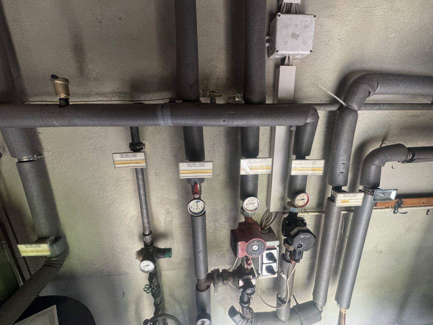 Isolierte Rohre und Manometer einer Heizungs- oder Wasserinstallation.
