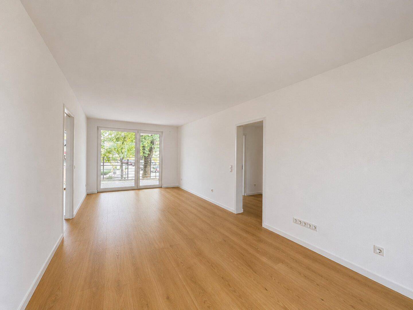 Geräumiges, helles Wohnzimmer mit Holzboden und großen Fenstern zum Außenbereich.