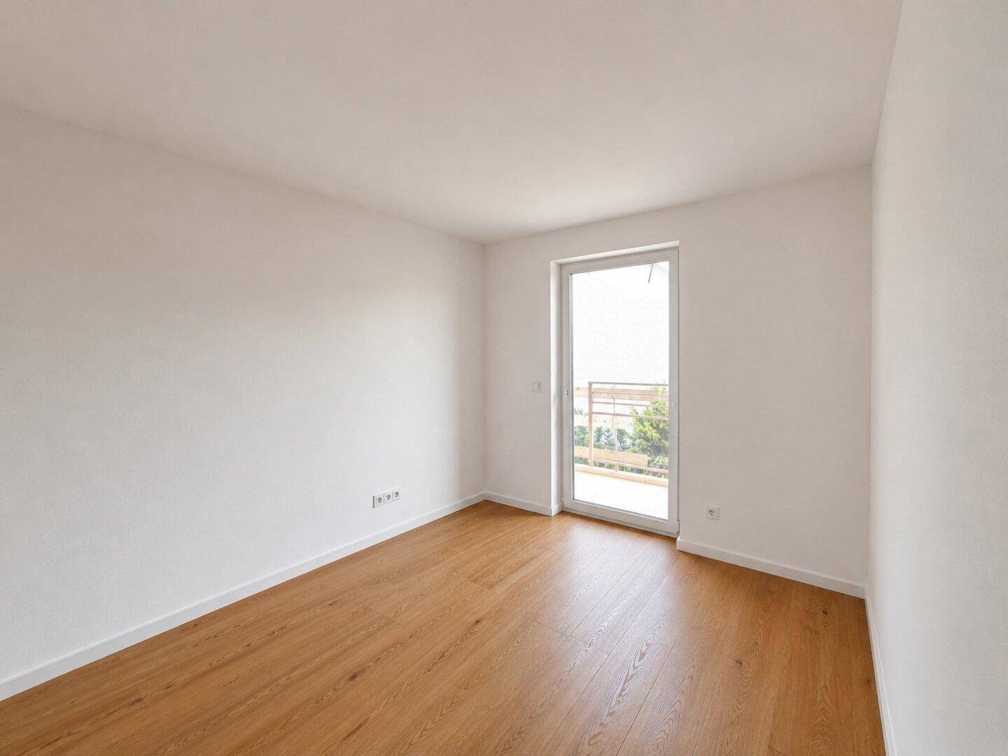 Helles Schlafzimmer mit Holzboden und Zugang zu einem kleinen Balkon.