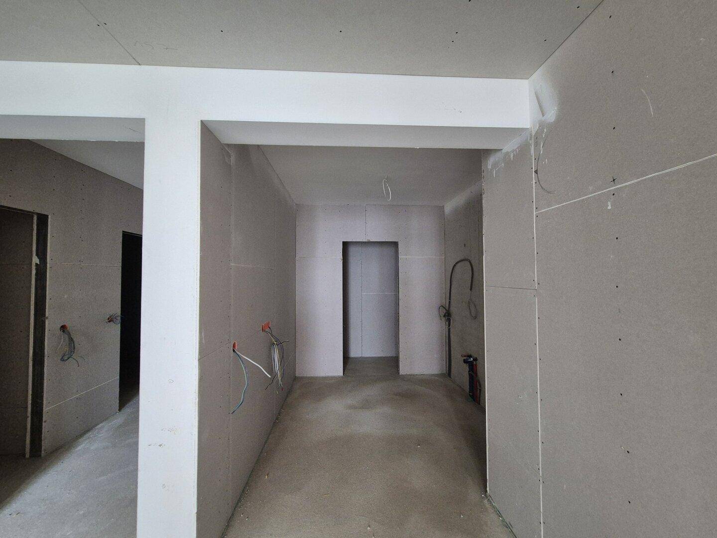 Rohbauküche mit Trockenbauwänden, Betonboden und vorbereiteten Anschlüssen für die Installation.