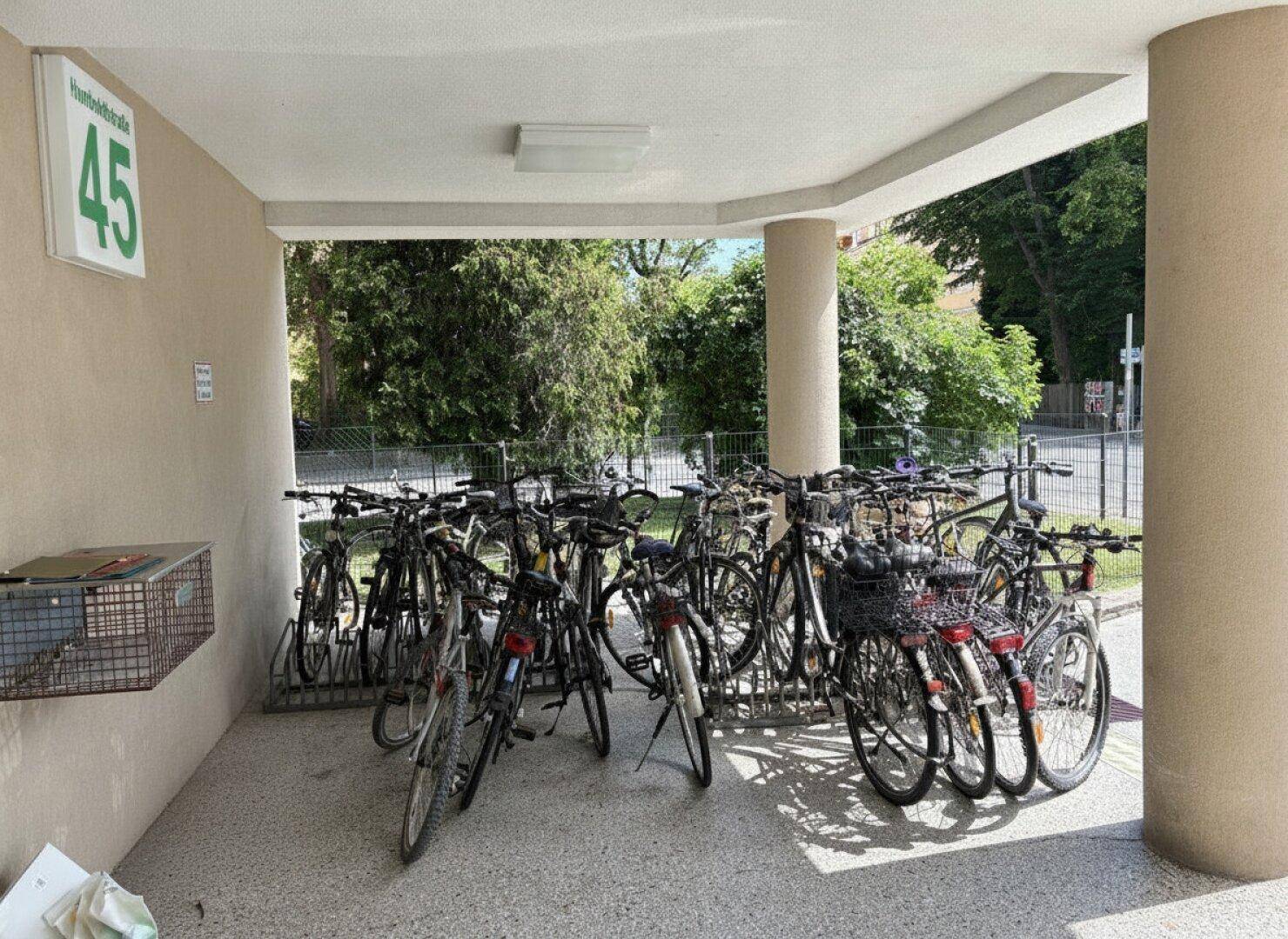 Überdachter Fahrradabstellplatz vor dem Gebäude mit zahlreichen abgestellten Fahrrädern.
