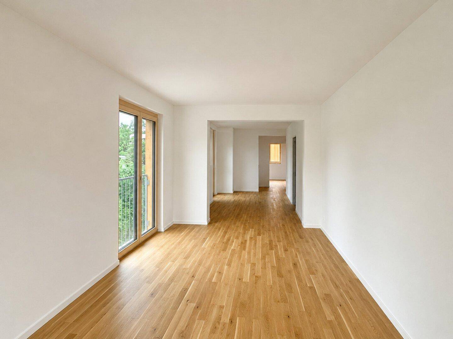 Geräumiges, helles Zimmer mit Holzboden und Zugang zu einem Balkon, ideal für offenes Wohnen.