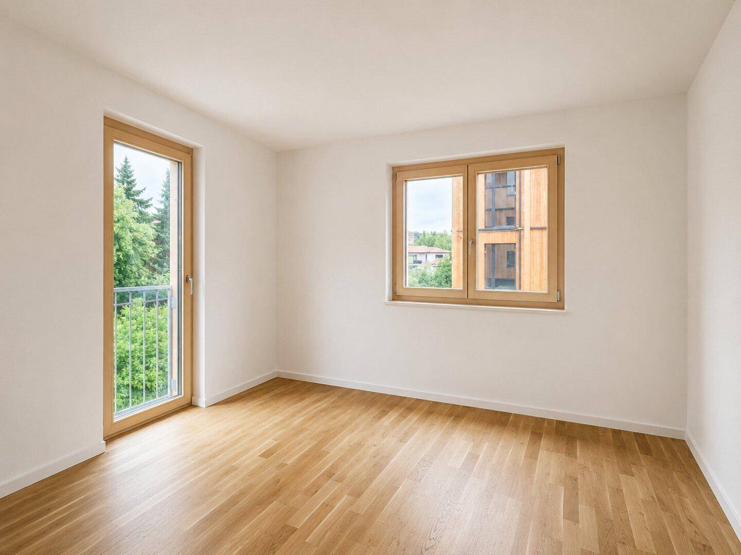 Leeres Schlafzimmer mit Holzboden und Fenster, das einen Blick auf die Umgebung ermöglicht.