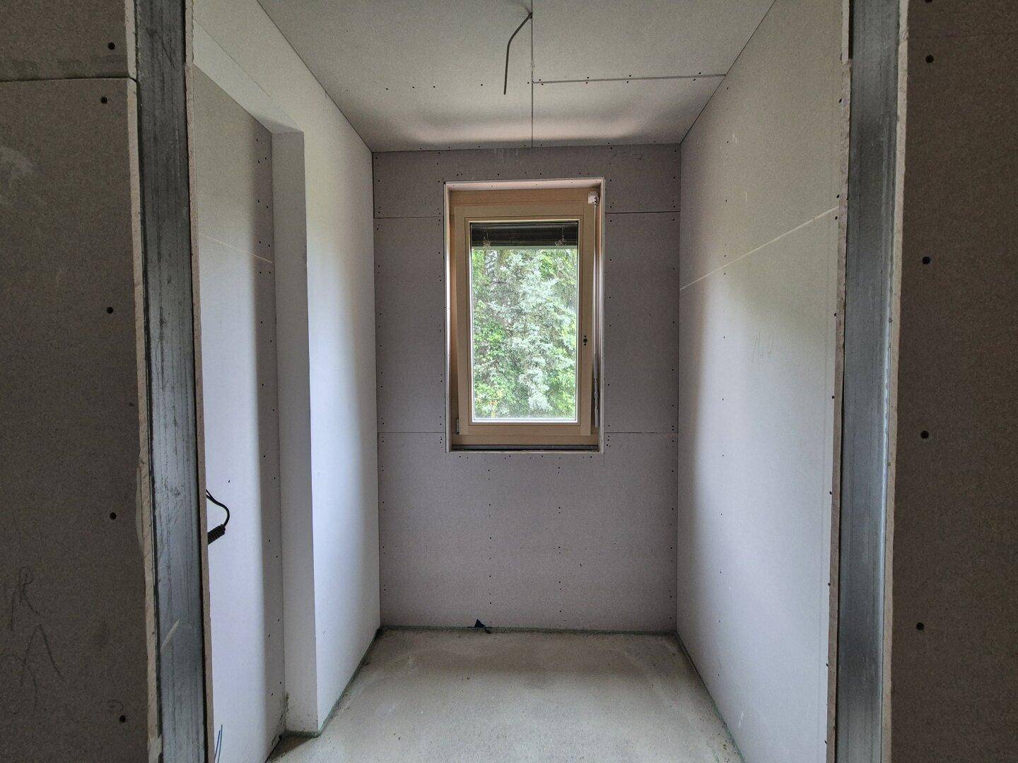 Kleiner Rohbauraum mit einem Fenster, ideal für ein Gäste-WC oder einen Abstellraum.