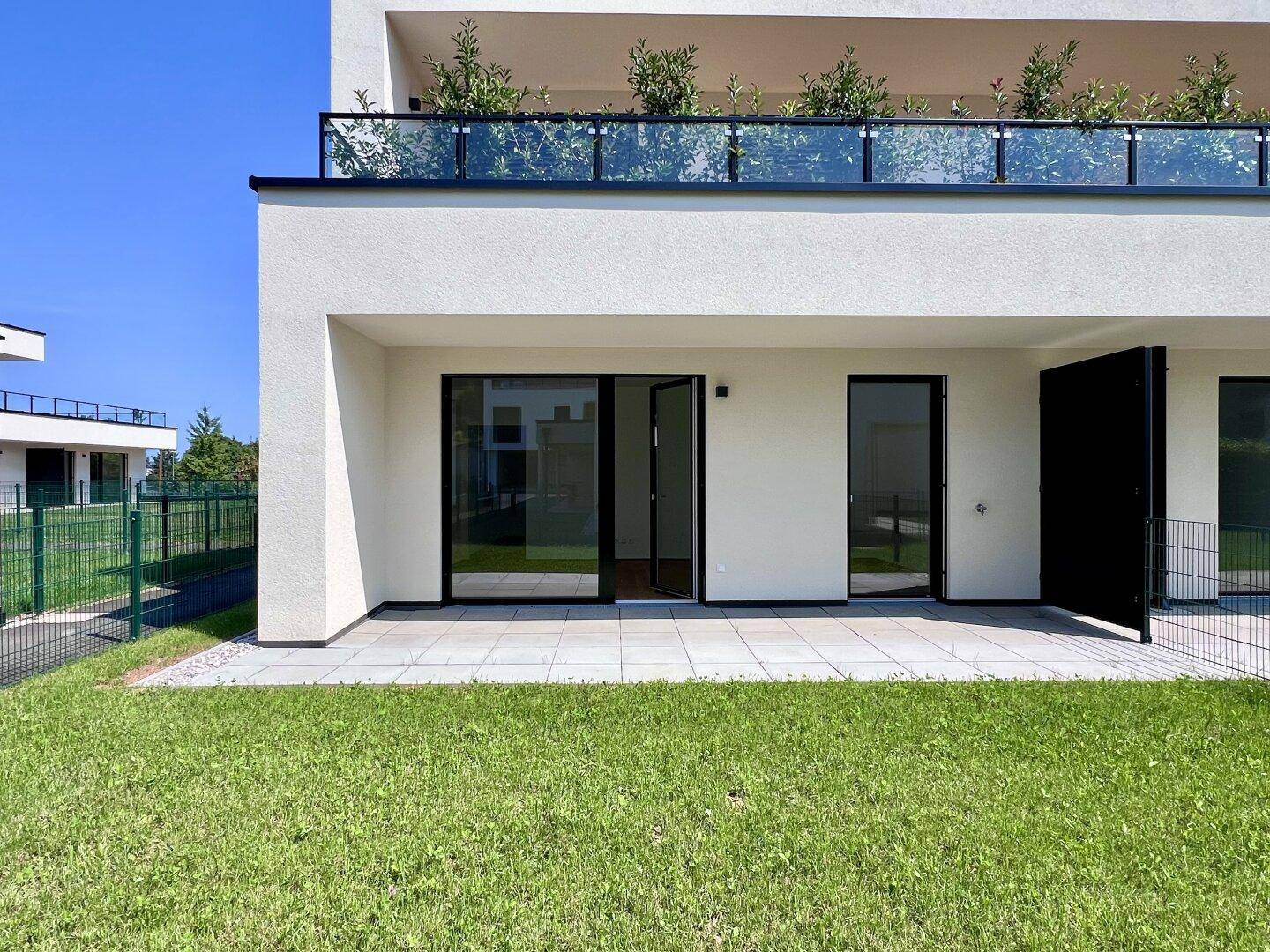 Nahaufnahme der modernen Erdgeschosswohnung mit Terrasse und direktem Zugang zum Garten.
