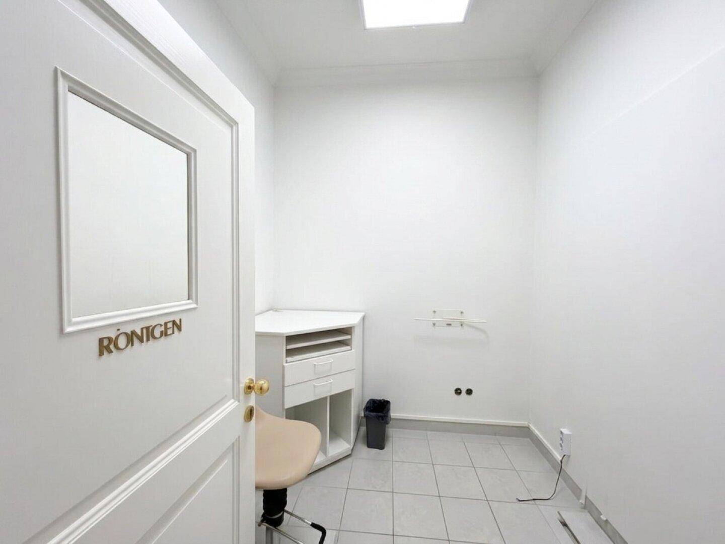 Kleiner, heller Raum mit Fliesenboden und einem Schrank, möglicherweise ein Röntgenraum oder Lager.