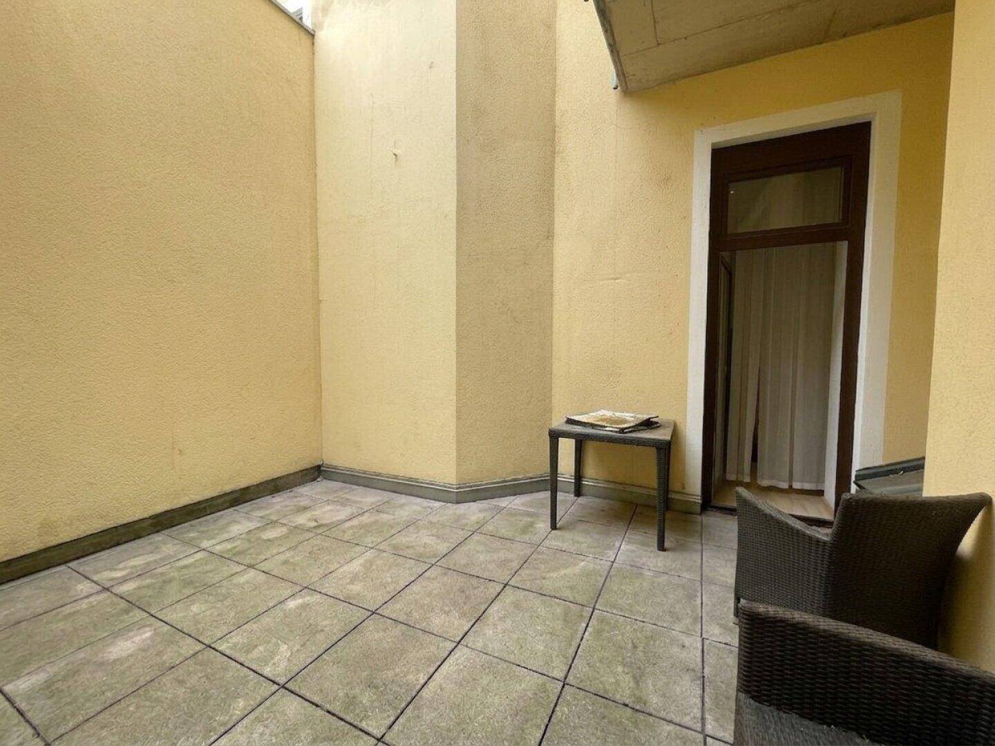 Ruhige Außenterrasse mit Fliesenboden und einem kleinen Tisch, ideal zum Entspannen.