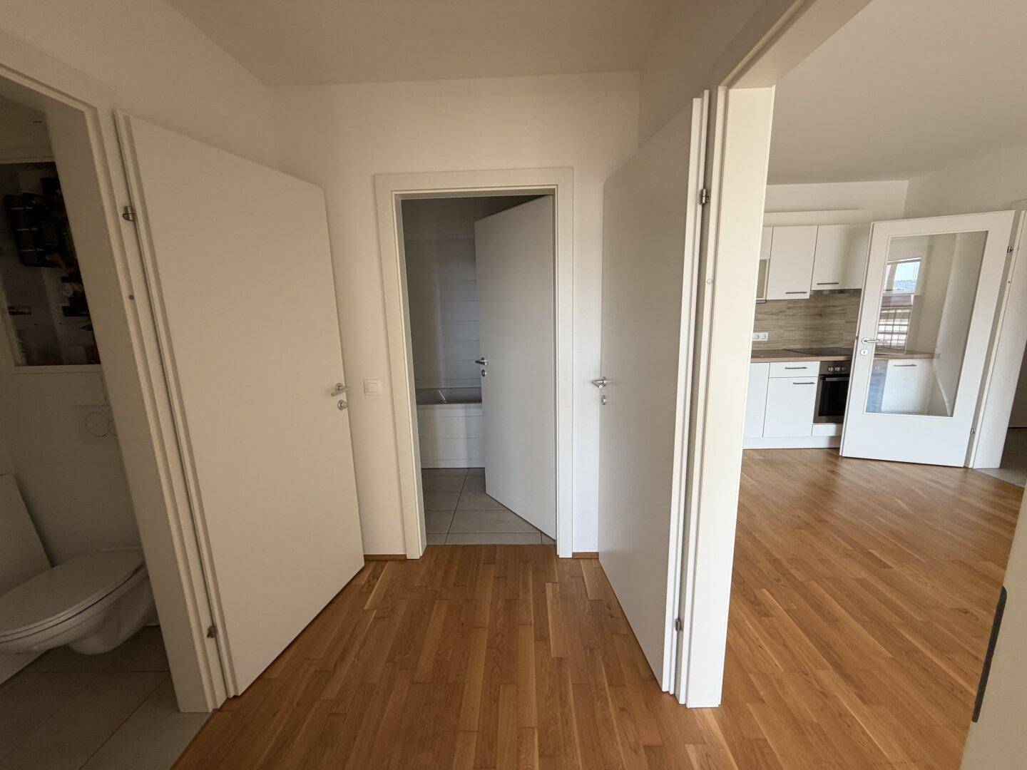 Heller Flur mit Holzboden und mehreren Türen, die zu den angrenzenden Räumen führen.