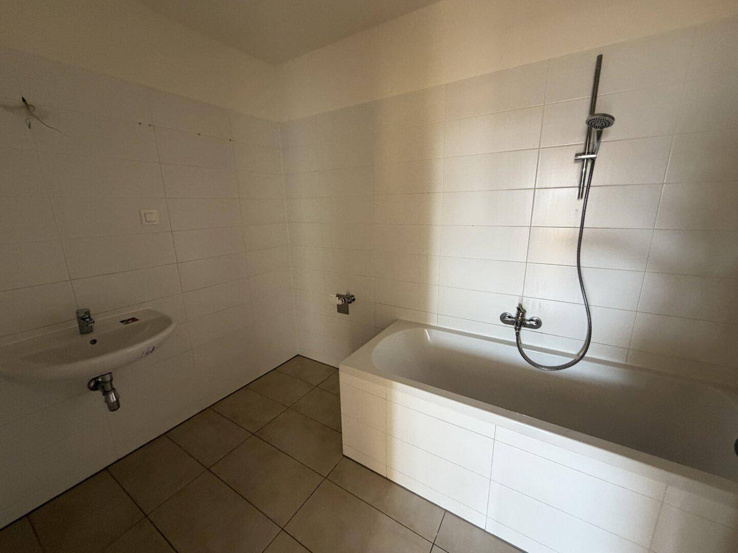 Badezimmer mit Badewanne, Waschbecken und weißen Fliesen, bereit für die persönliche Gestaltung.