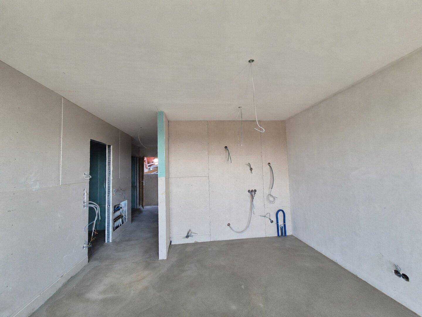 Rohbauküche mit Trockenbauwänden, Betonboden und sichtbaren Installationen für Wasser und Strom.
