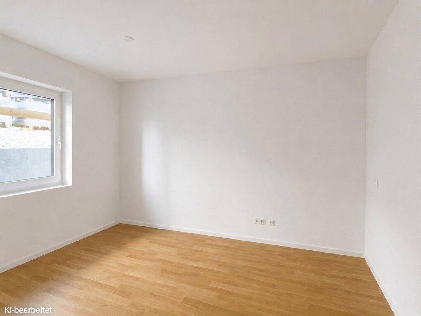Helles Zimmer mit weiß gestrichenen Wänden, Holzboden und einem Fenster, das Tageslicht hereinlässt.