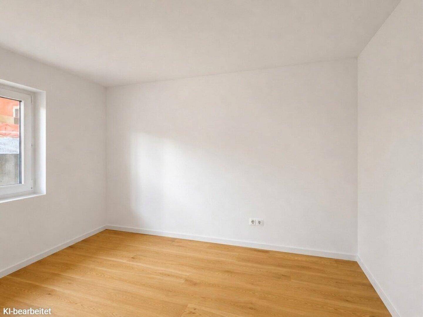 Leerer Raum mit hellem Holzboden und einem Fenster, das viel Tageslicht hereinlässt.