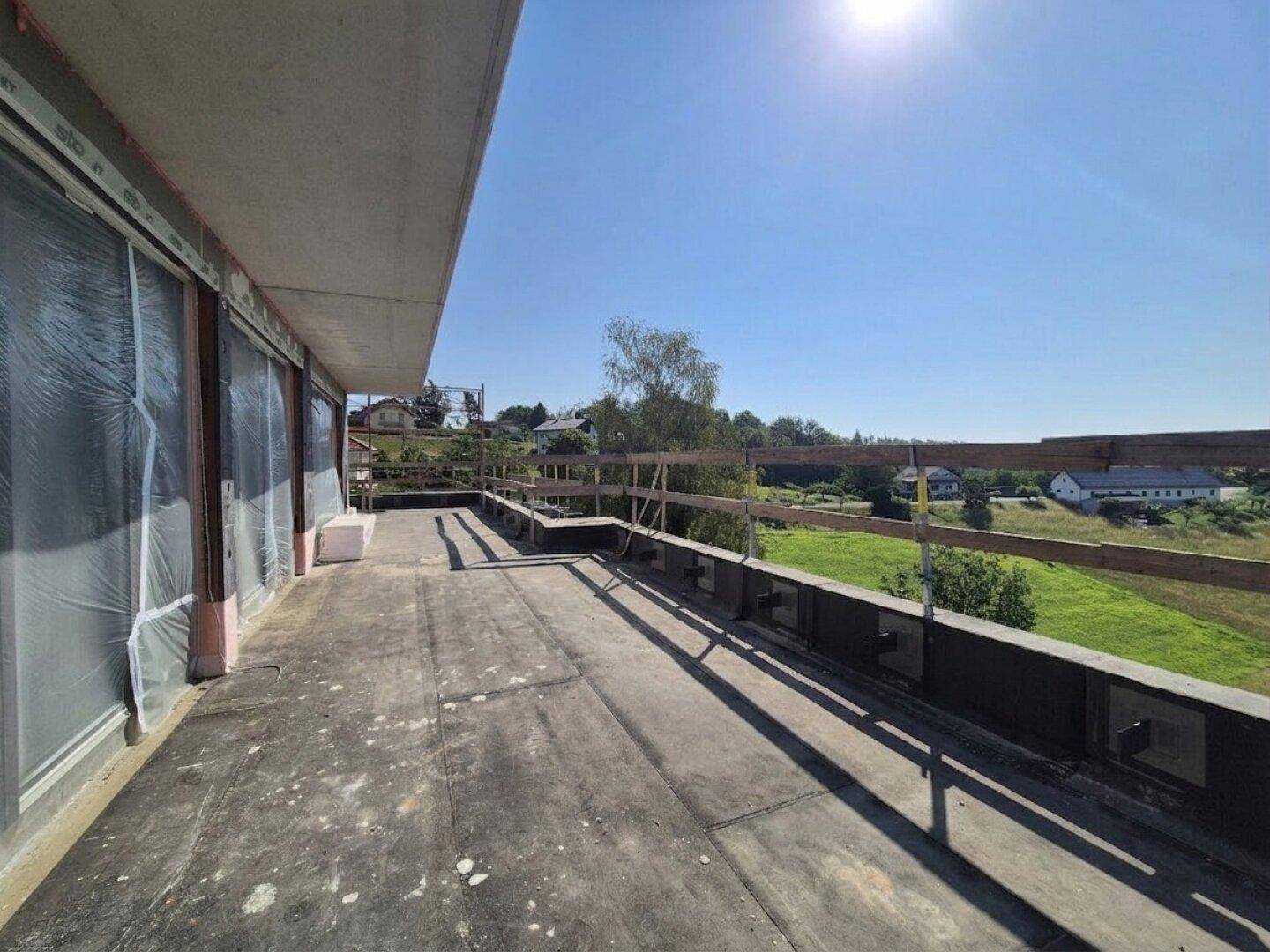 Große Terrasse im Bau mit provisorischem Geländer und weitem Blick auf die Landschaft.
